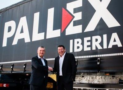 Representantes addingplus y pall-ex dándose la mano delante de camión